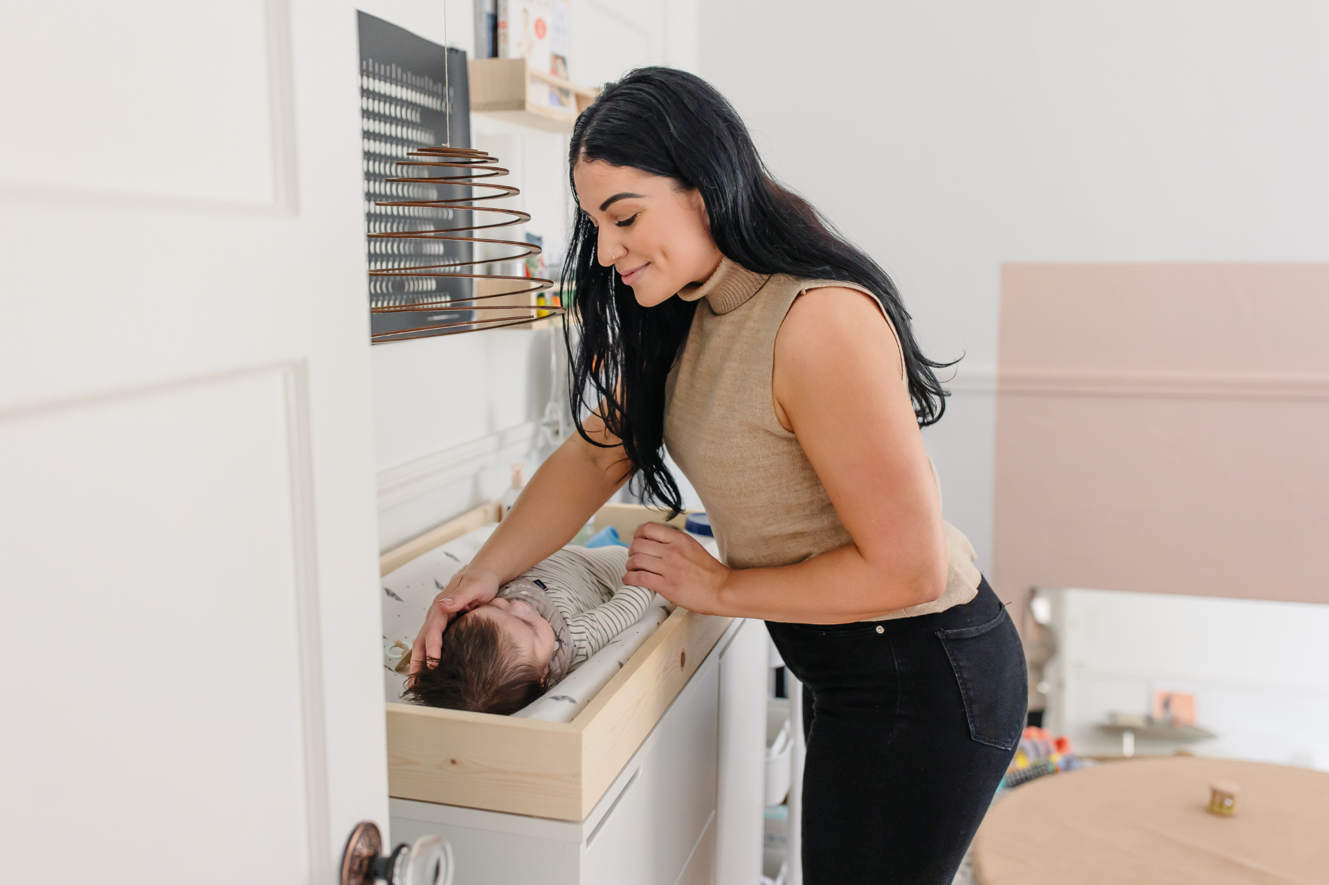 Doula tenderly attending to a baby on a changing table