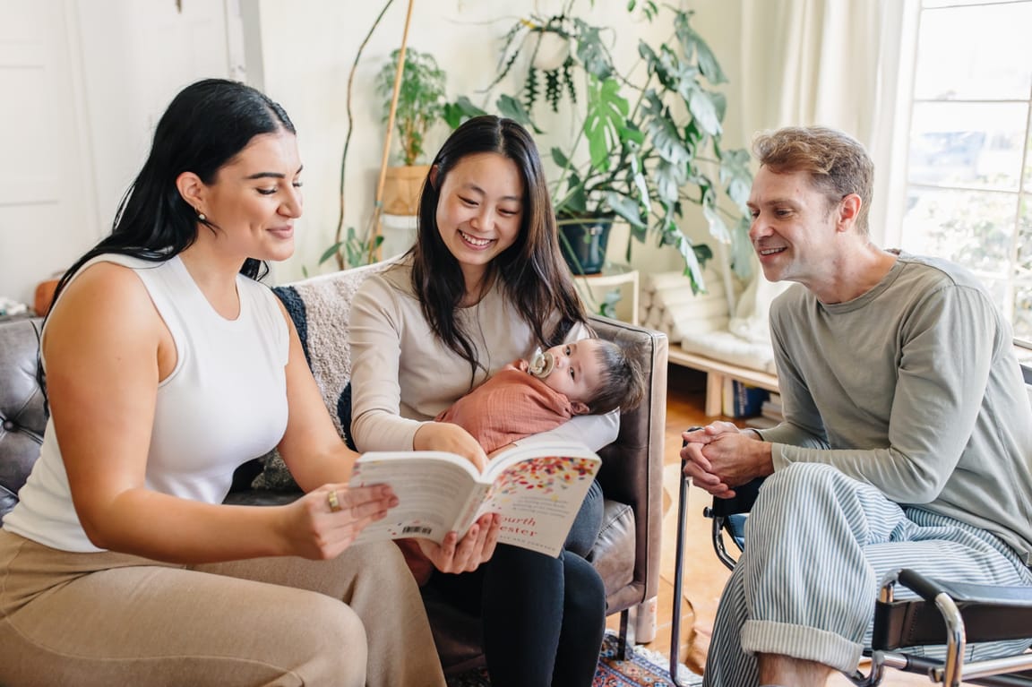 Ashlee leading a warm postpartum education session with a family — two parents and a baby learning together