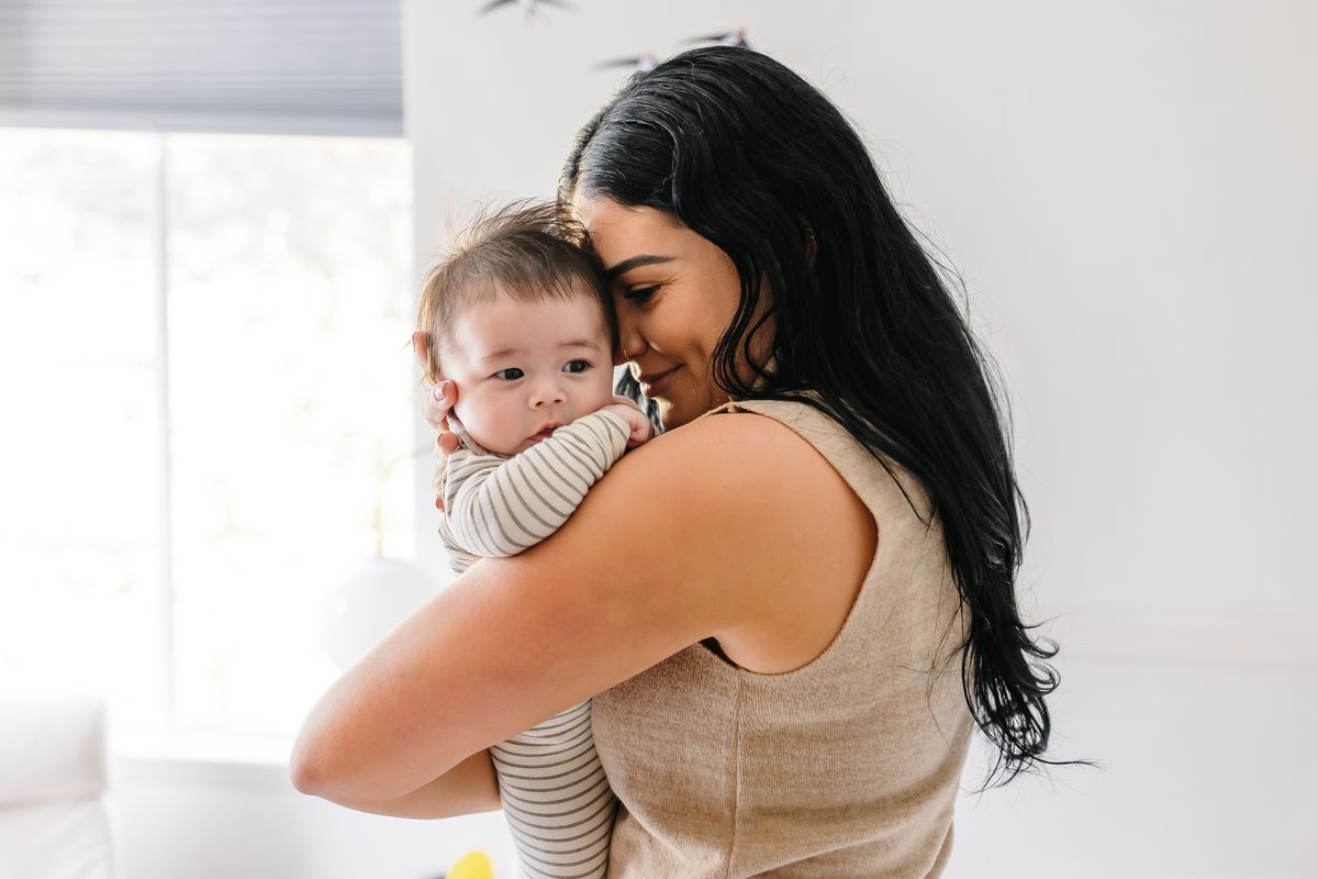 Ashlee McKenzie holding a baby close, cheek to cheek, in a bright, sunlit room