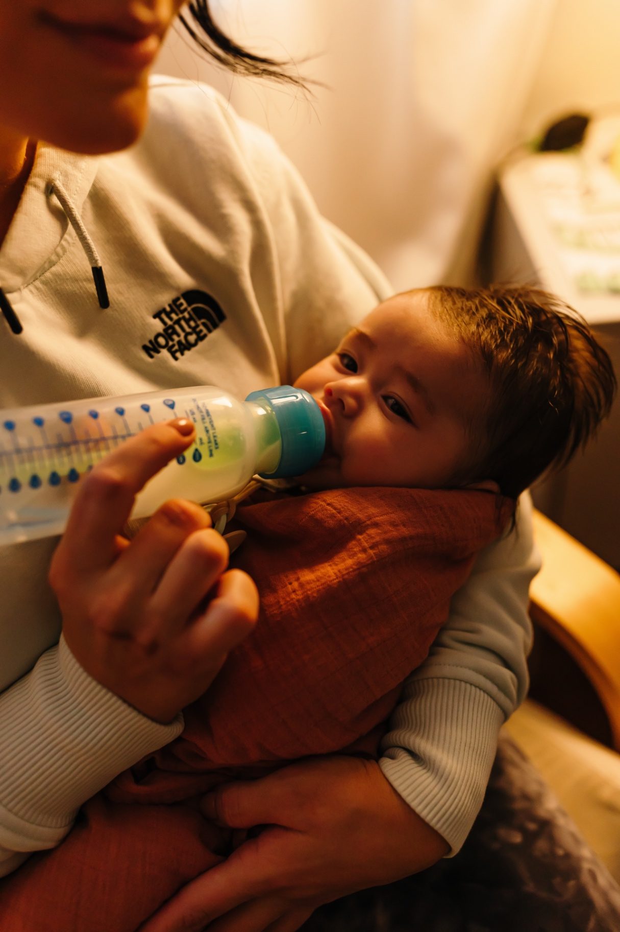 A quiet lamp-lit bottle feeding during an overnight newborn care shift